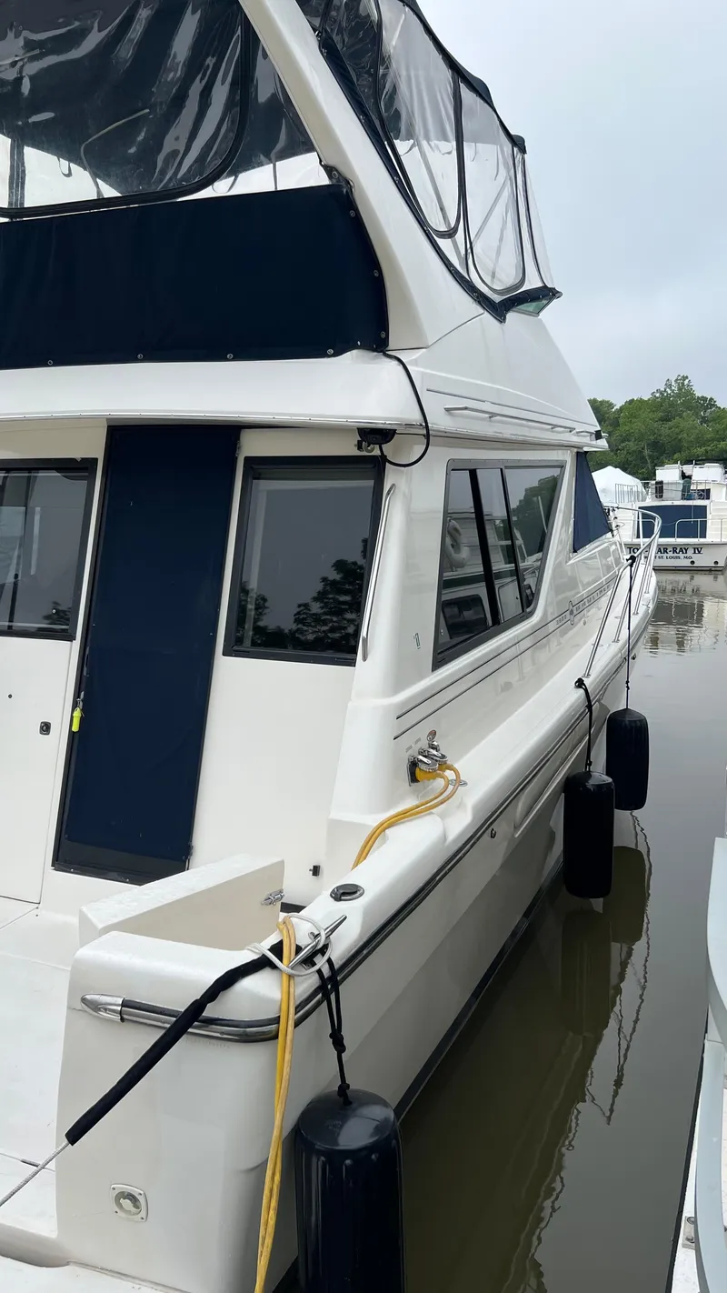 Slide: The Image of 1999 Bayliner 3988 Motoryacht docked, featuring sleek design and blue canopy. - 2