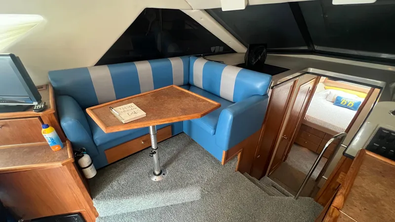 Slide: The Image of Interior of 1999 Bayliner 3988 Motoryacht with blue seating and wooden table. - 7