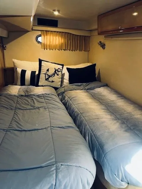 Slide: The Image of 2003 Regal 3860 Commodore cabin with twin beds and nautical-themed decor. - 11