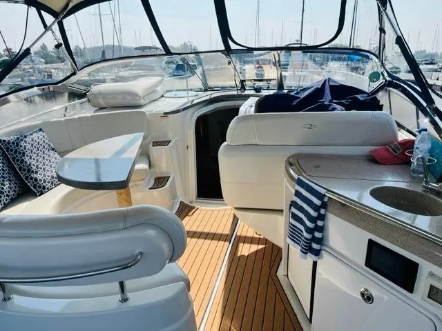 Slide: The Image of 2003 Regal 3860 Commodore yacht interior with seating, table, and kitchenette in a marina setting. - 9