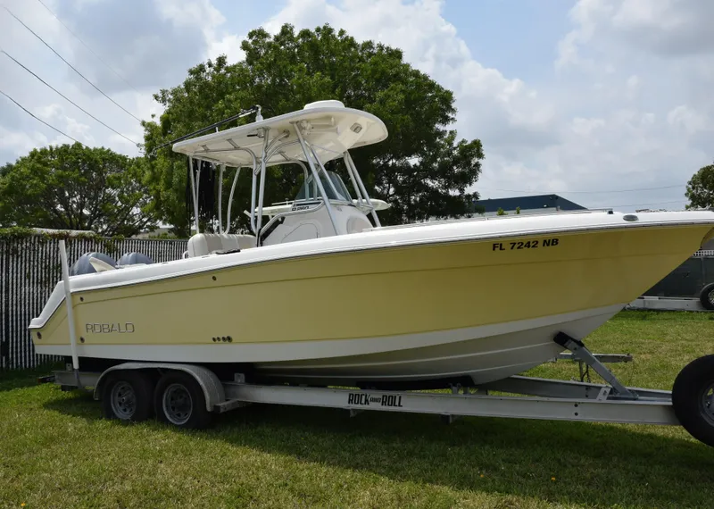 The Image of 2006 Robalo R260 Center Console boat on a trailer in a grassy area. - 0