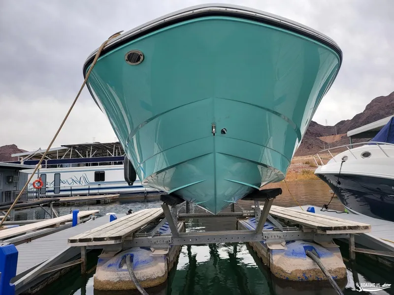 Slide: The Image of 2023 Monterey M22 boat docked on a lift, turquoise hull, marina background. - 11
