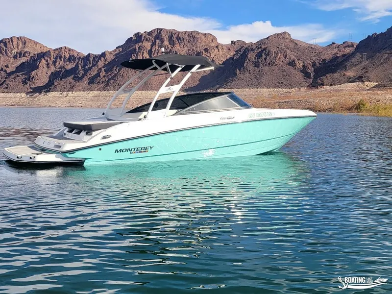 Slide: The Image of 2023 Monterey M22 boat on a serene lake with rocky hills in the background. - 12