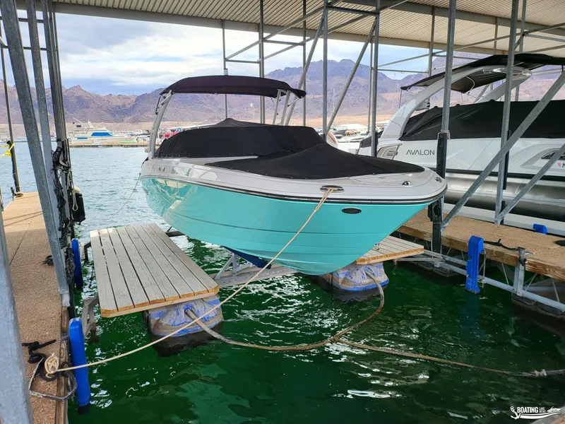 Slide: The Image of 2023 Monterey M22 boat docked in a marina, covered and elevated above water. - 9