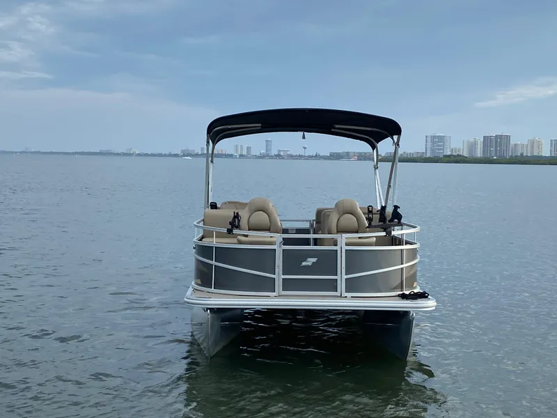 Slide: The Image of 2022 Starcraft LX 18 F pontoon boat on calm water with city skyline in background. - 3