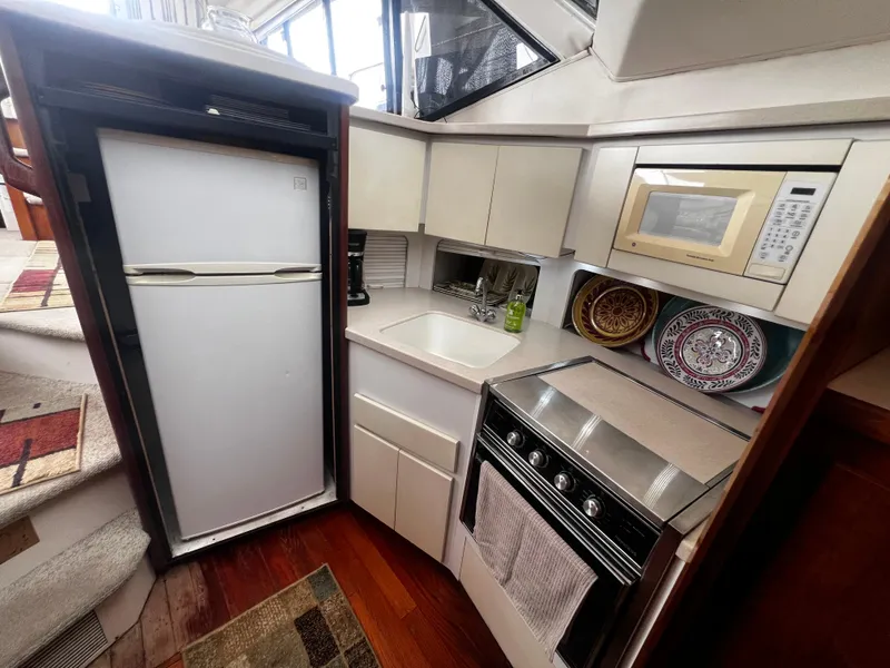 Slide: The Image of Compact kitchen in a 1993 Carver 350 Aft Cabin yacht with fridge, microwave, and stove. - 27
