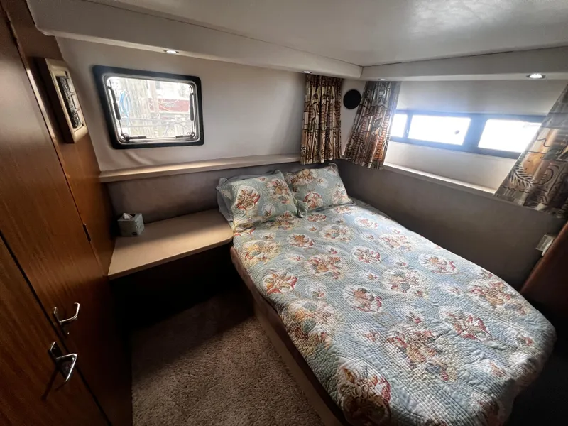 Slide: The Image of 1993 Carver 350 Aft Cabin bedroom with floral bedspread and porthole windows. - 45