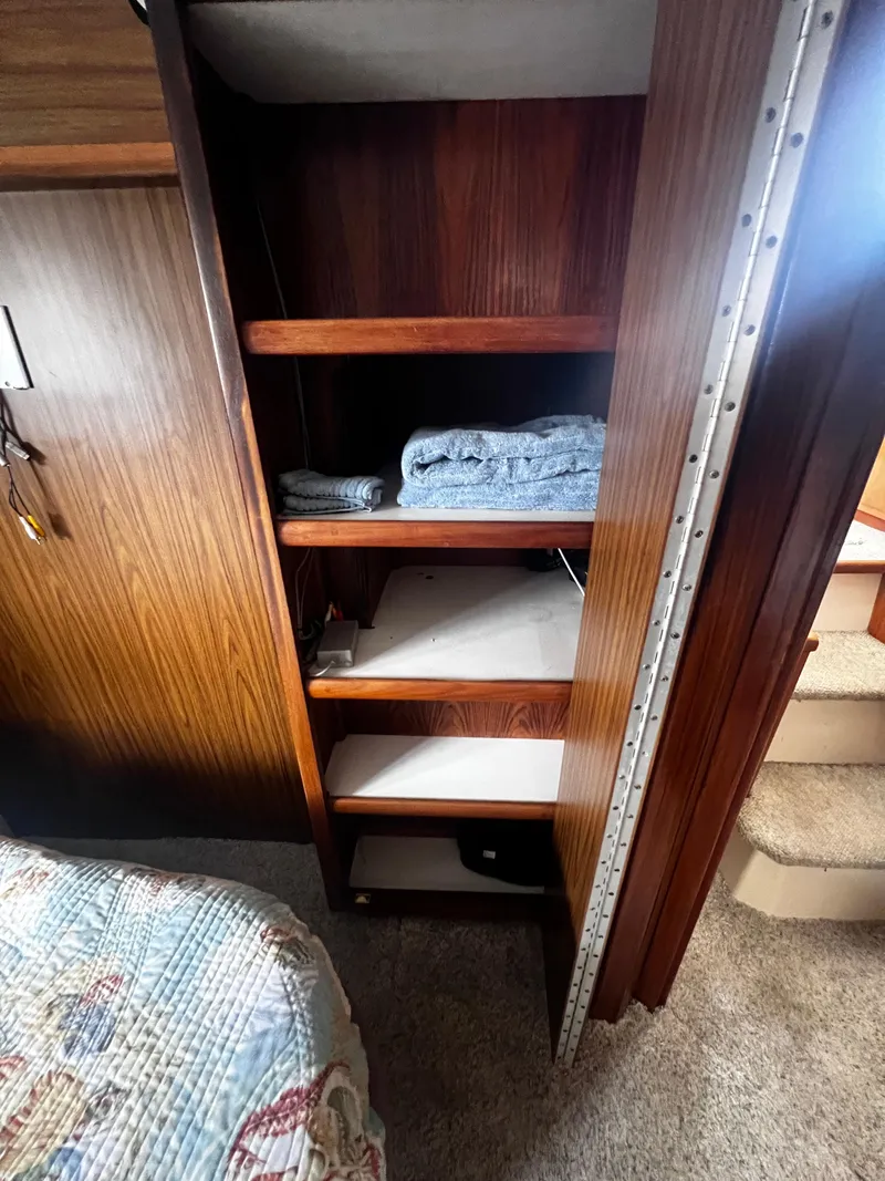 Slide: The Image of Wooden shelves inside a 1993 Carver 350 Aft Cabin boat, with folded towels. - 46