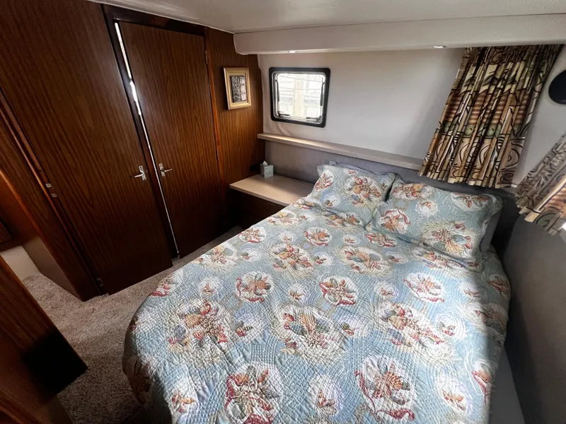 Slide: The Image of 1993 Carver 350 Aft Cabin bedroom with floral bedspread and wood-paneled closet. - 48