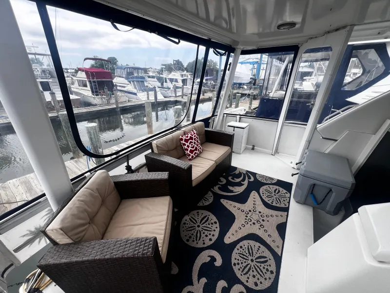 Slide: The Image of 1993 Carver 350 Aft Cabin interior with marina view, wicker seating, and nautical-themed rug. - 5