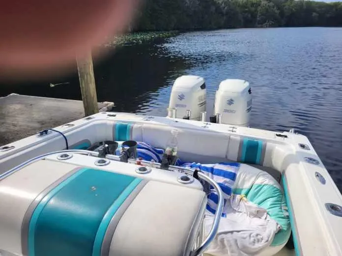 Slide: The Image of 1994 Fountain 31 CC boat with twin outboard motors docked on a calm lake. - 6