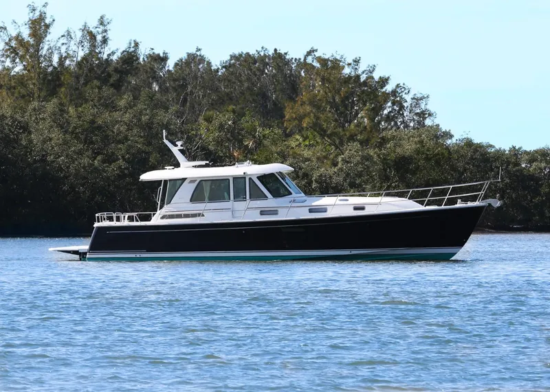 The Image of 2025 Sabre 48 Salon Express yacht on calm water, surrounded by trees. - 0