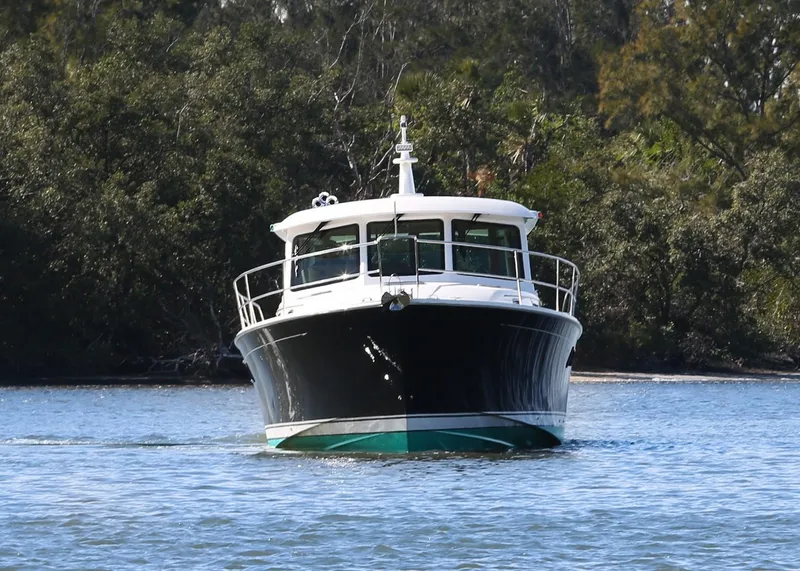 Slide: The Image of 2025 Sabre 48 Salon Express yacht cruising on a calm river with lush greenery. - 2