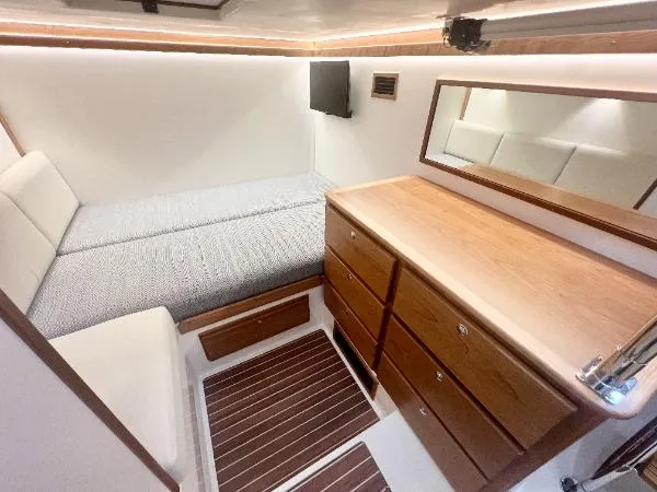 Slide: The Image of Interior of 2025 Sabre 48 Salon Express, featuring a cozy cabin with bed and wooden dresser. - 24