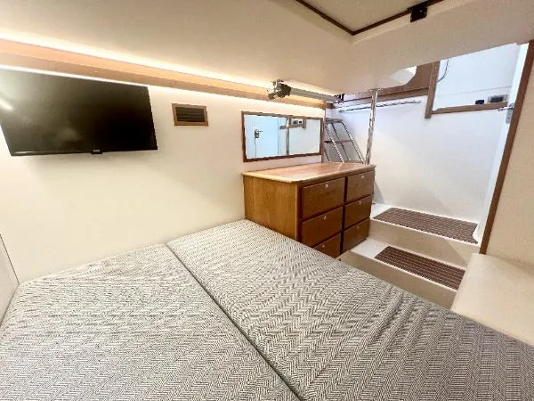Slide: The Image of Interior of 2025 Sabre 48 Salon Express, featuring a cozy bedroom with TV and wooden cabinetry. - 27