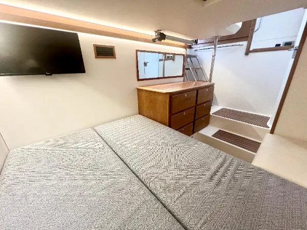 Slide: The Image of Interior of 2025 Sabre 48 Salon Express, featuring a cozy bedroom with TV and wooden cabinetry. - 28