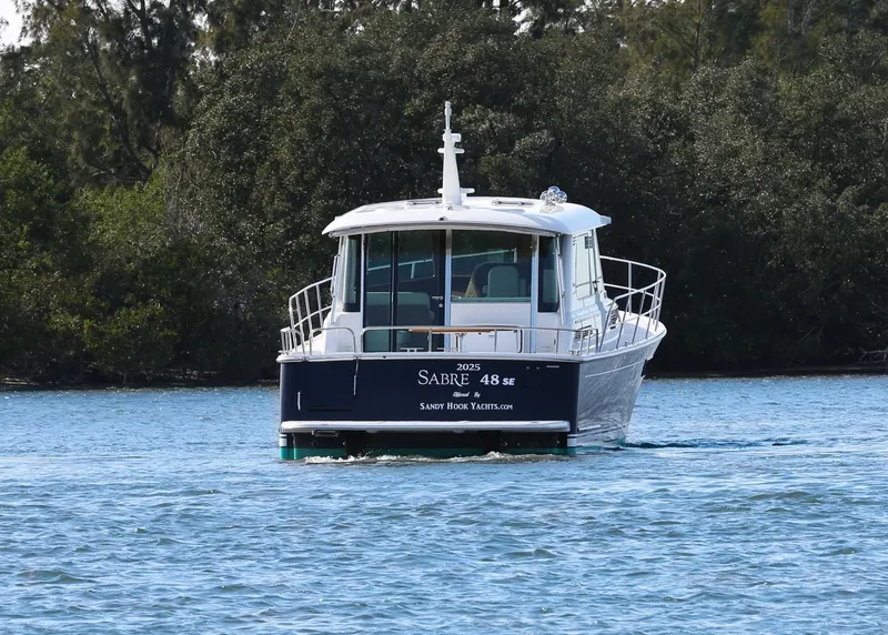Slide: The Image of 2025 Sabre 48 Salon Express yacht cruising on a serene waterway. - 4