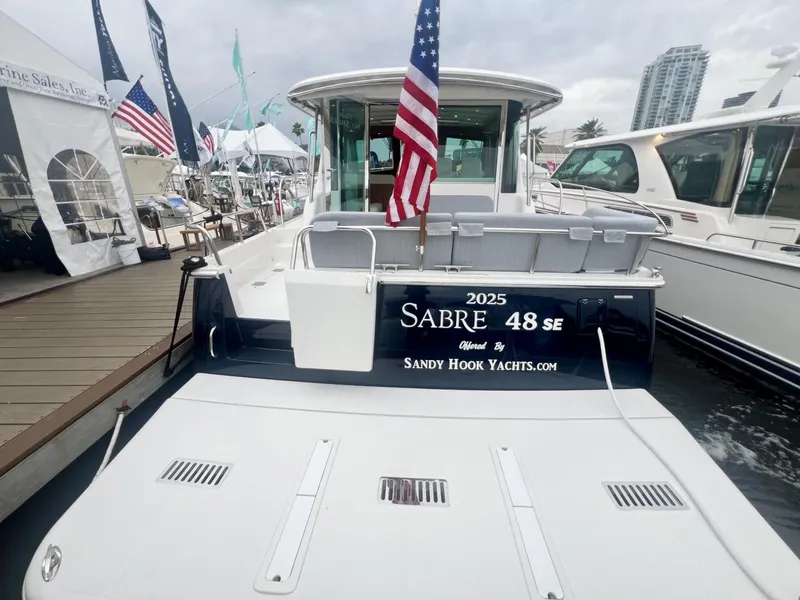 Slide: The Image of 2025 Sabre 48 Salon Express yacht docked, featuring American flag and Sandy Hook Yachts branding. - 6