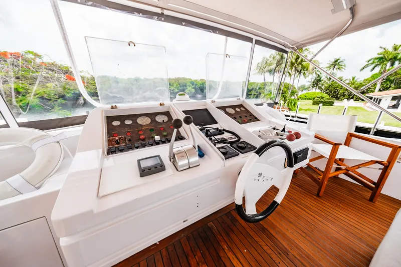 Slide: The Image of Monte Fino 94 Motor Yacht 1992 helm station with wooden deck and lush surroundings. - 49