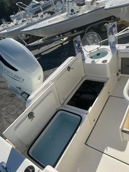 Slide: The Image of 2023 Sea Born LX24 Center Console LE with open storage compartments and Suzuki outboard motor. - 8