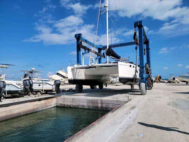 Slide: The Image of A 2009 Fusion 40 catamaran being lifted by a boat hoist at a marina. - 30