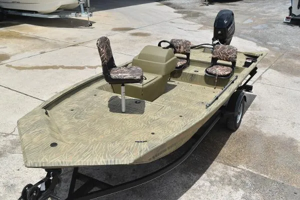 Slide: The Image of 2024 Tracker Grizzly 1754 SC fishing boat with camouflage seats on a trailer. - 2
