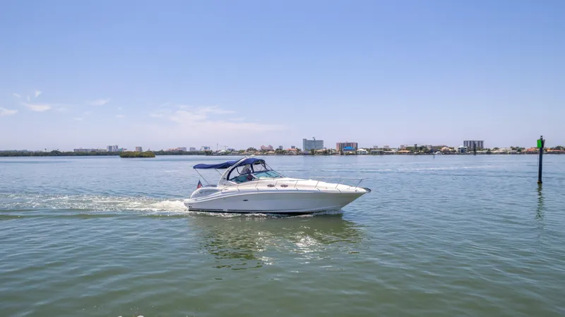 Slide: The Image of 2005 Sea Ray 340 Sundancer cruising on calm waters with cityscape in the background. - 1