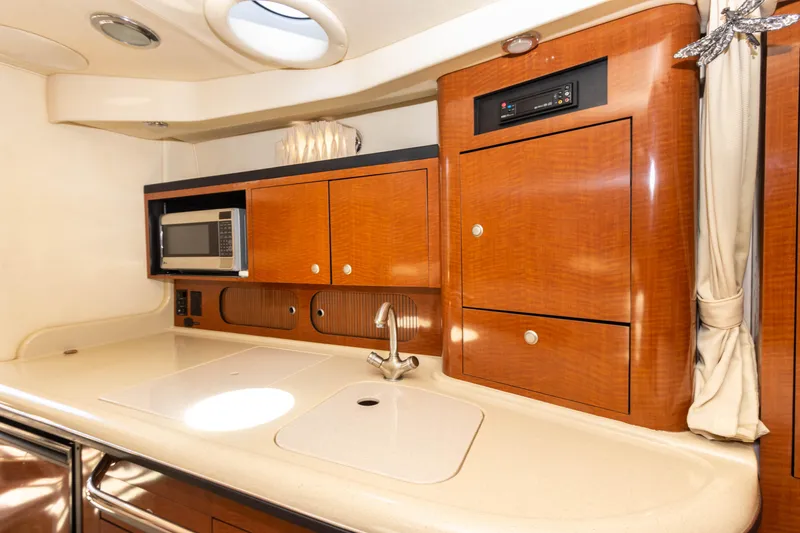 Slide: The Image of 2005 Sea Ray 340 Sundancer galley with microwave, sink, and wooden cabinetry. - 37