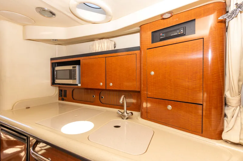 Slide: The Image of 2005 Sea Ray 340 Sundancer galley with microwave, sink, and wooden cabinetry. - 38