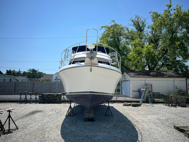 Slide: The Image of 1987 Carver Voyager boat on dry dock, front view, sunny day, trees in background. - 1