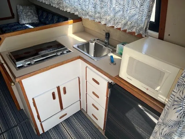 Slide: The Image of Compact kitchen in a 1987 Carver Voyager boat with stove, sink, and microwave. - 14