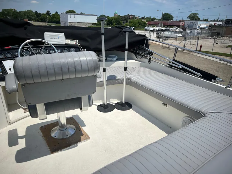 Slide: The Image of 1987 Carver Voyager boat cockpit with gray seating and steering wheel, docked outdoors. - 25