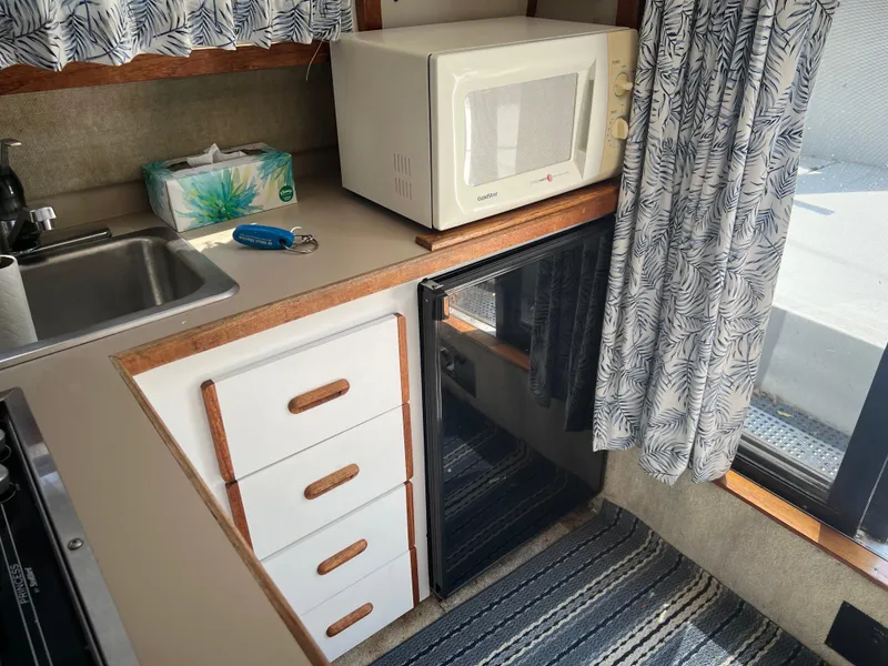 Slide: The Image of Compact kitchen in a 1987 Carver Voyager with microwave, sink, and mini fridge. - 17