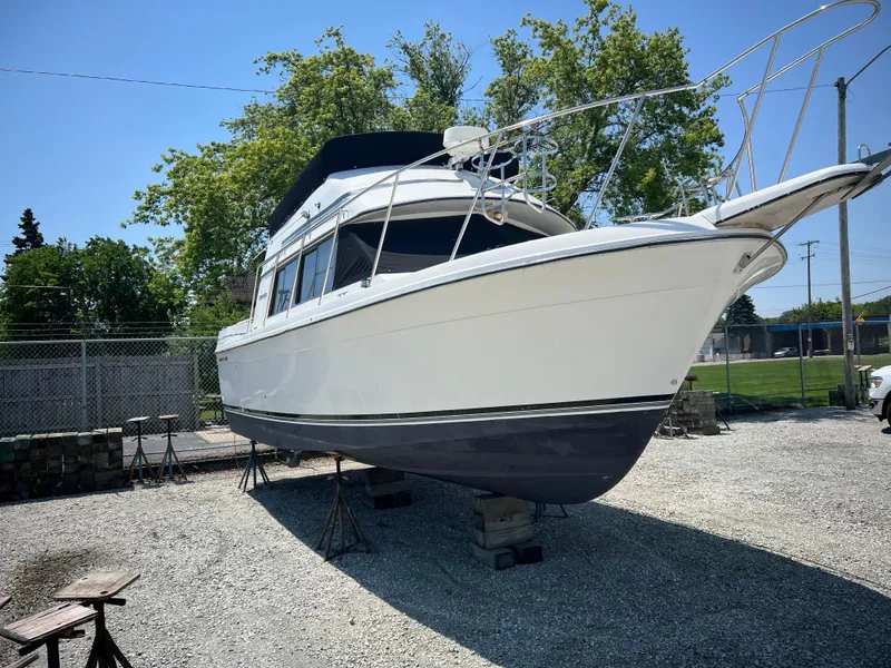 Slide: The Image of 1987 Carver Voyager boat on stands, white hull, outdoor storage, sunny day. - 2