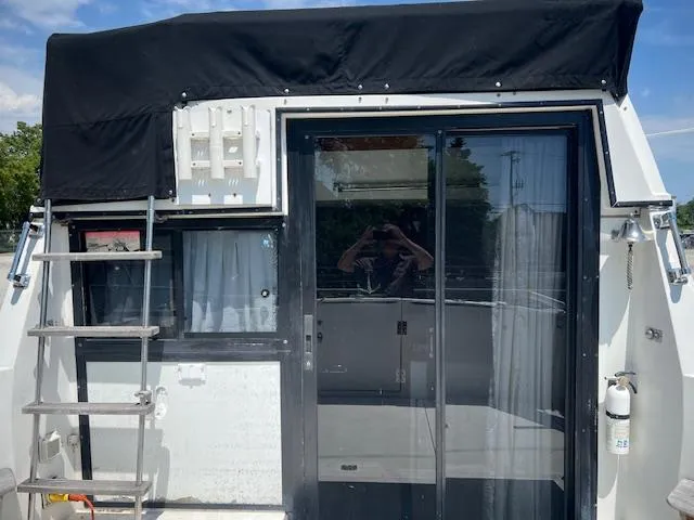 Slide: The Image of 1987 Carver Voyager boat with sliding glass door and ladder, featuring black canopy. - 6