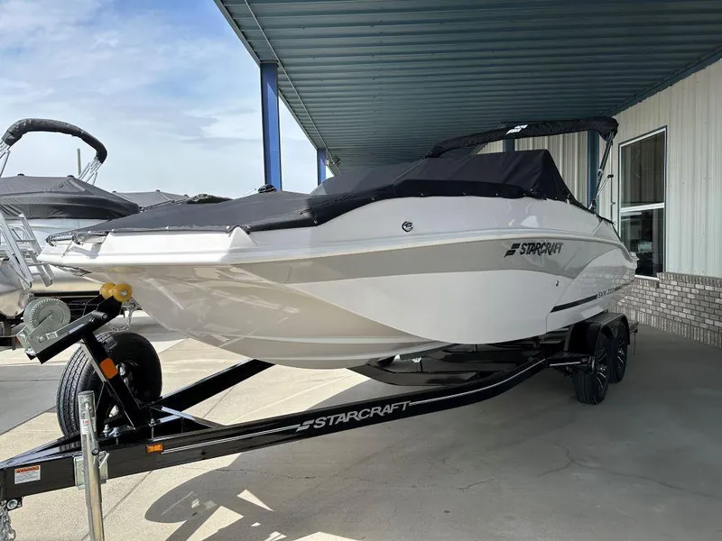 The Image of 2024 Starcraft SVX 210 OB DC boat on trailer, covered and parked outdoors. - 0