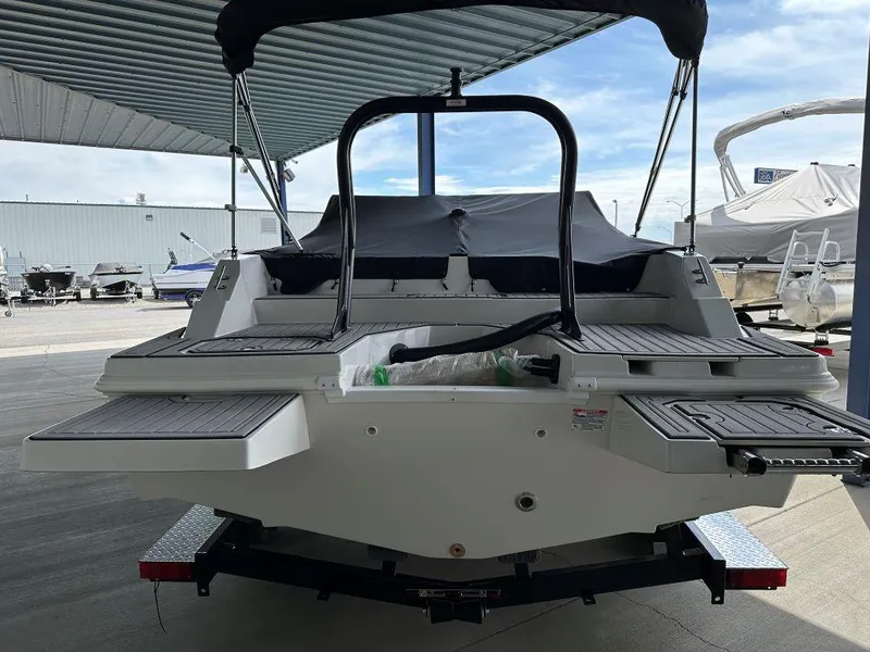 Slide: The Image of 2024 Starcraft SVX 210 OB DC boat rear view, docked under a canopy. - 3