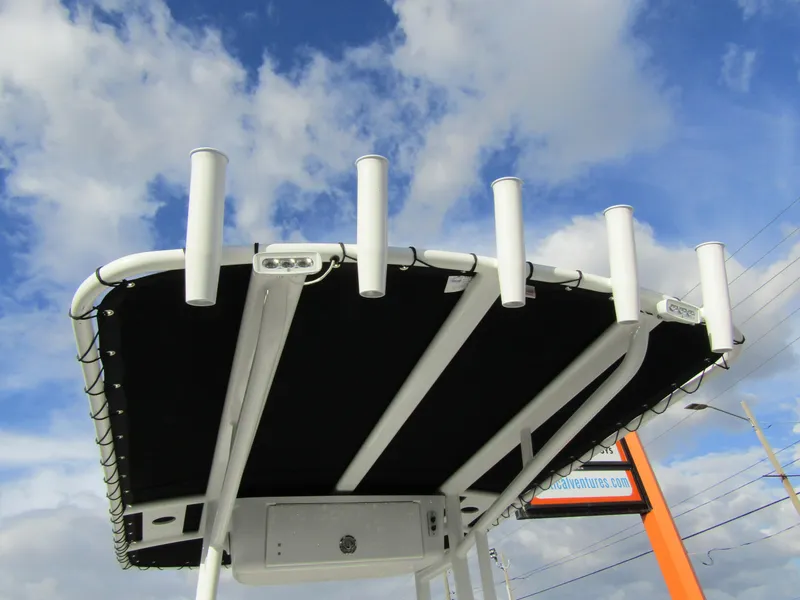 Slide: The Image of 2023 Tidewater 198 CC Adventure T-top with rod holders against a blue sky. - 23