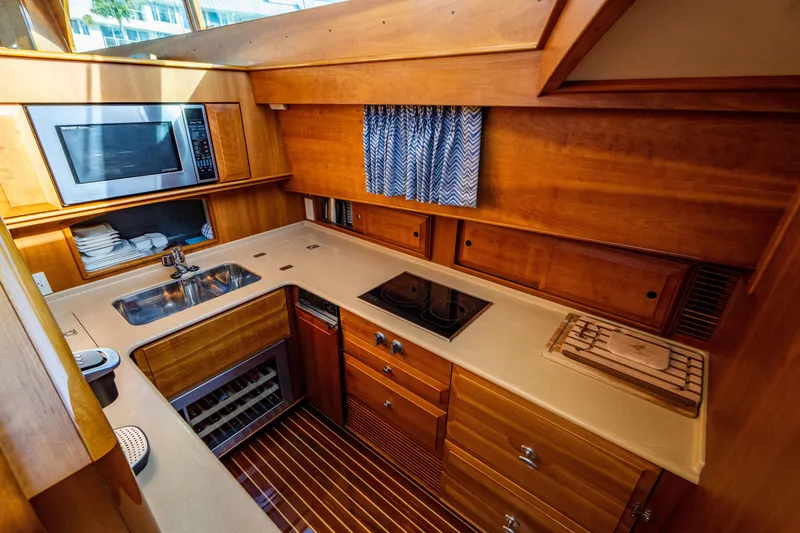 Slide: The Image of 2007 Hinckley Talaria 55 FB yacht kitchen with wood cabinetry, sink, stove, and microwave. - 21