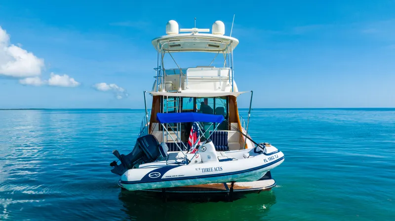 Slide: The Image of 2007 Hinckley Talaria 55 FB yacht on calm blue waters, rear view with tender boat. - 5