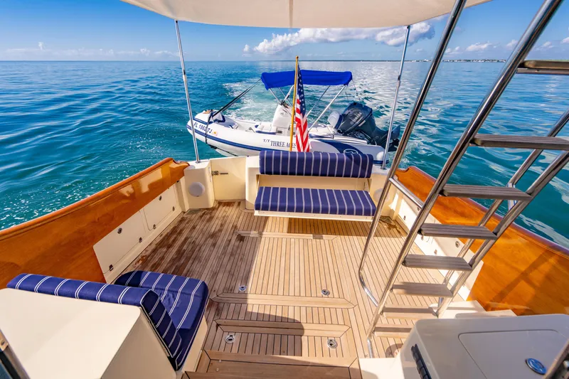 Slide: The Image of 2007 Hinckley Talaria 55 FB yacht deck with striped seating, ocean view, and small boat. - 8