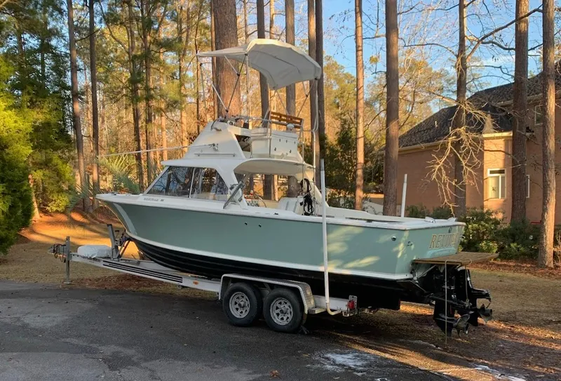 Slide: The Image of 1966 Bertram 25 boat on a trailer in a wooded residential area. - 1