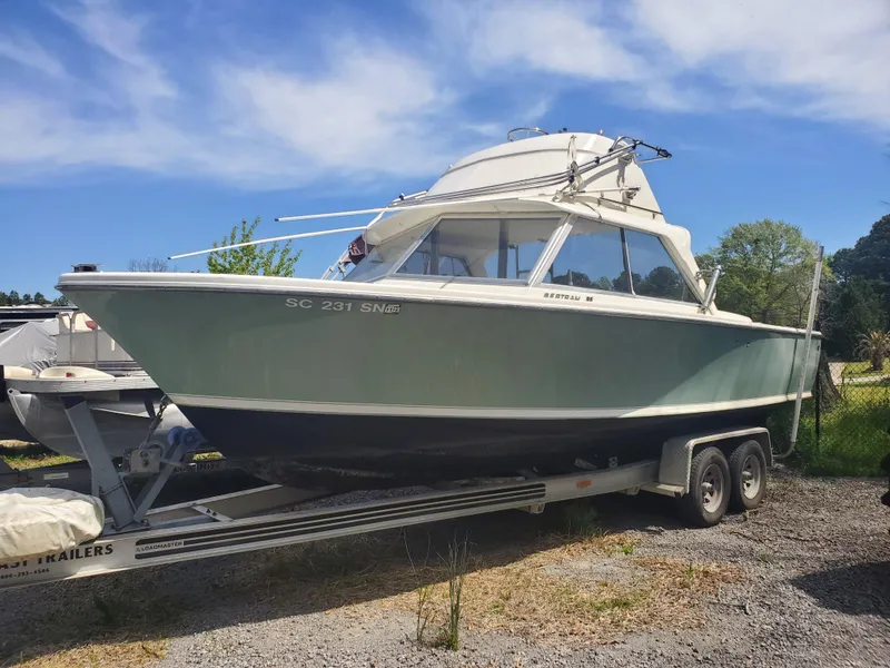 Slide: The Image of 1966 Bertram 25 boat on a trailer under a clear sky. - 2