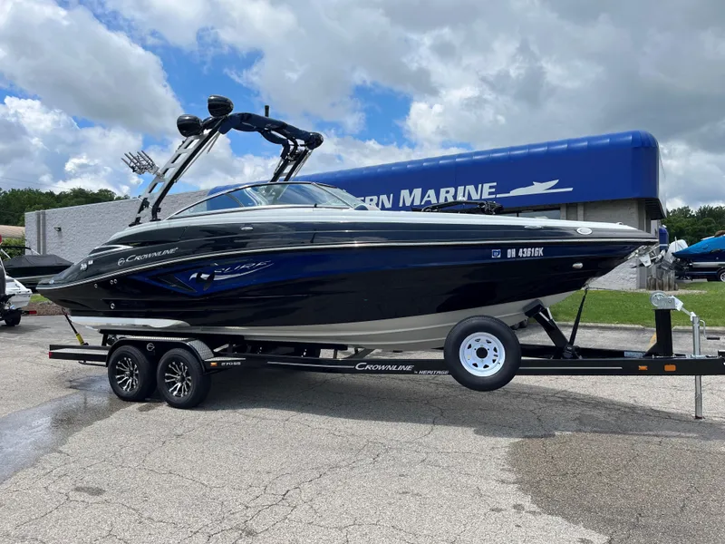 Slide: The Image of 2023 Crownline 270 SS SURF boat on a trailer outside a marine dealership. - 0
