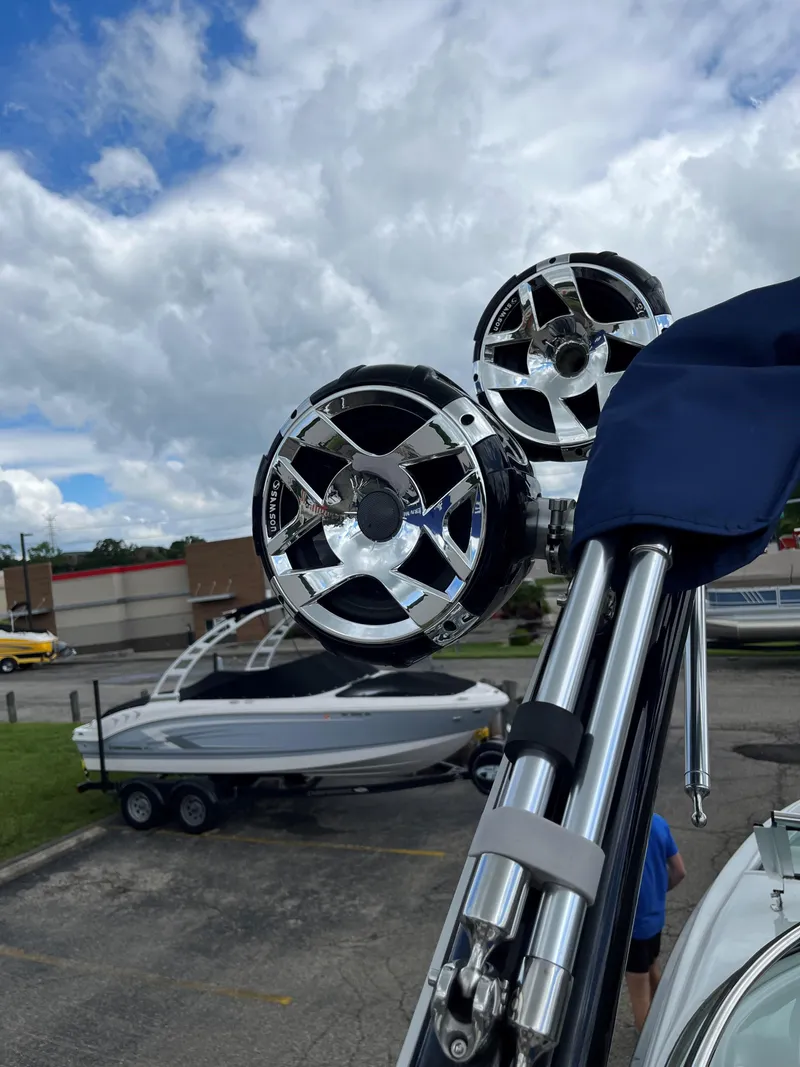 Slide: The Image of 2023 Crownline 270 SS SURF boat with mounted speakers in a parking lot. - 15