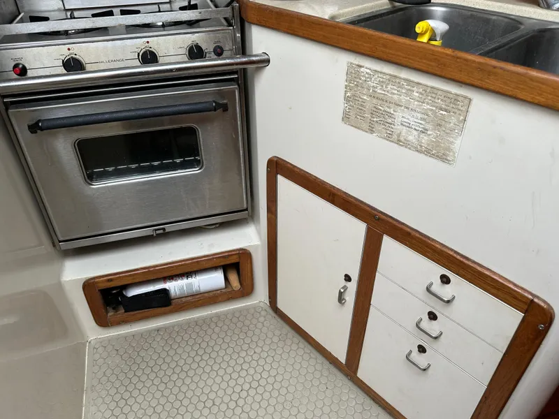 Slide: The Image of 1994 Catalina 320 yacht kitchen with stove, cabinets, and sink area. - 13