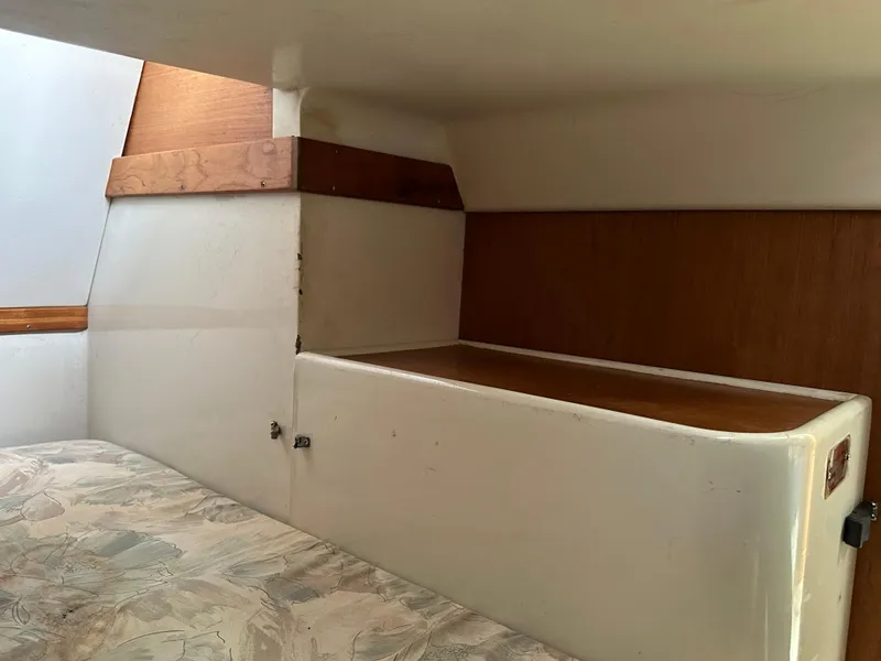 Slide: The Image of Interior cabin of a 1994 Catalina 320 sailboat, featuring wooden accents and a cushioned berth. - 26