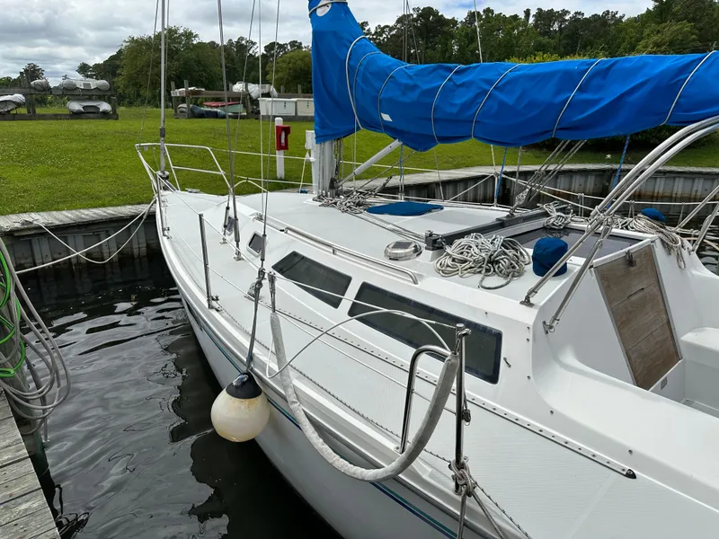 Slide: The Image of Catalina 320 sailboat from 1994 docked, featuring blue sail cover and clean white deck. - 3
