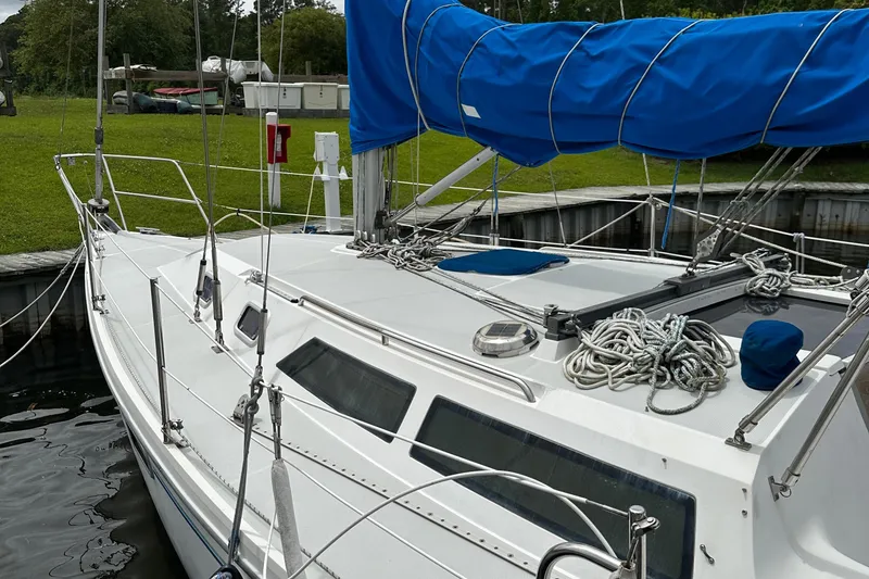 Slide: The Image of 1994 Catalina 320 sailboat docked, featuring blue sail cover and neatly coiled ropes. - 7