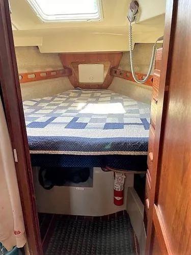 Slide: The Image of 1986 O'Day 35 sailboat cabin with quilted bed, wooden interior, and overhead hatch. - 13